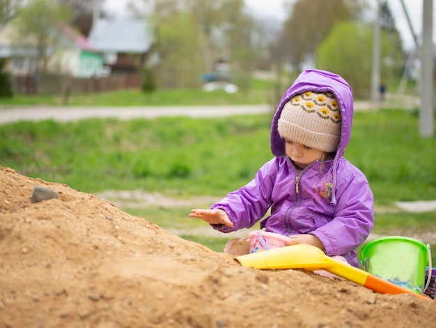 Baby speelt in het zand met een schop en een emmer