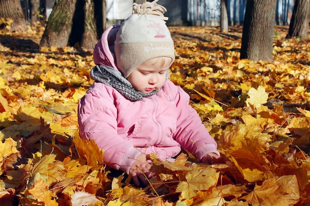 baby speelt met gele herfstbladeren in het park