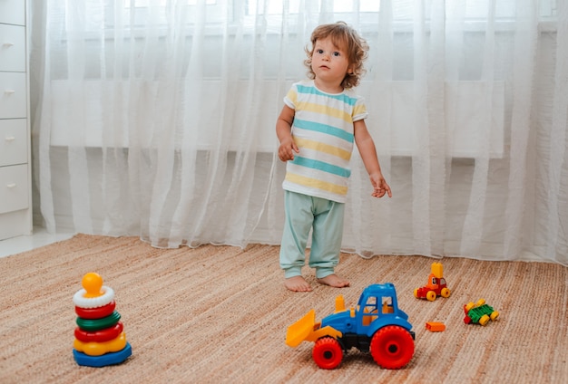 Baby speelt op de vloer in de kamer in educatief plastic speelgoed.