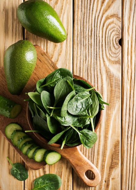 Spinaci e avocado in ciotola di legno sull'ingrediente sano verde della tavola