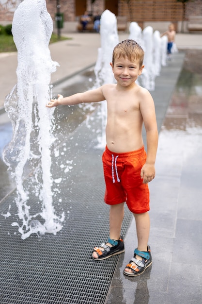 Baby staat in de fontein veel spatten het kind lacht een vrolijke gelukkige jeugd