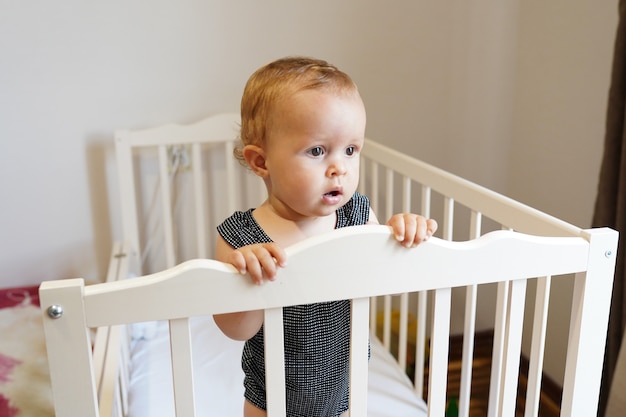 Baby standing in crib. cute Baby girl , childhood