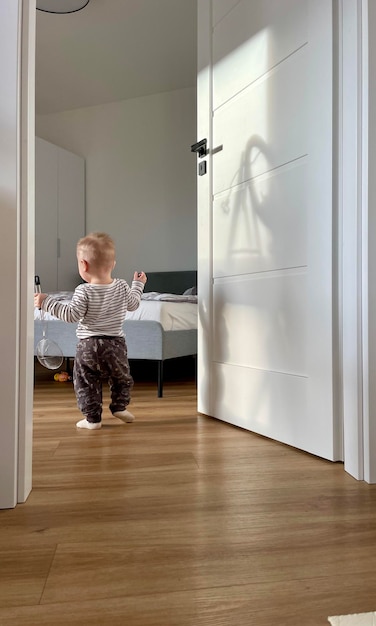 a baby stands in front of a door that has a shadow on it