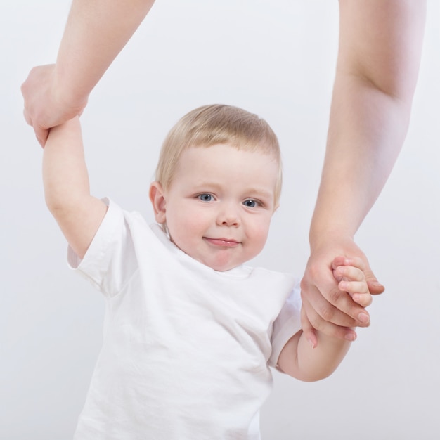 Baby takes first steps holding mom's hand