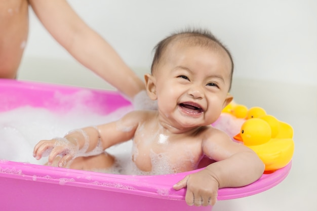 baby taking a bath in bathtub and playing with foam bubbles