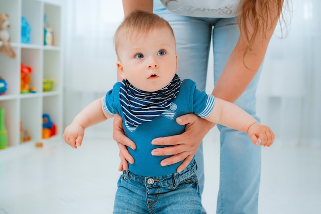 Il bambino muove i primi passi con l'aiuto della madre a casa