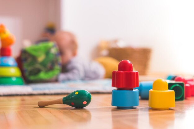 Baby toddler playing concept Colorful rattle and blocks in the foreground playing baby in the blurry background