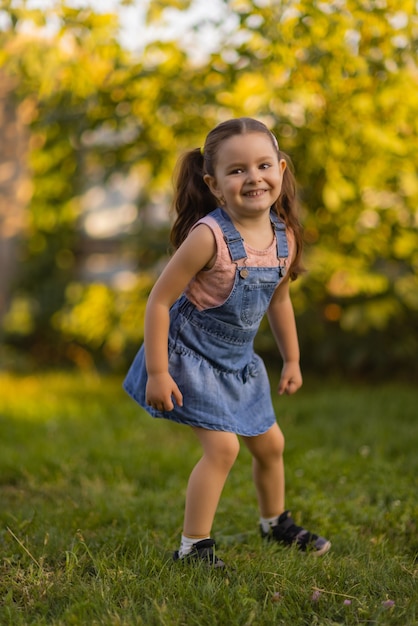 Baby toddler running on green lawn near the house