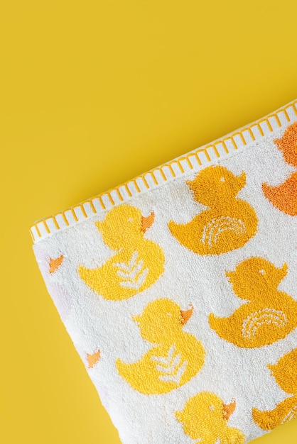 Baby towel with cute ducks on yellow background.