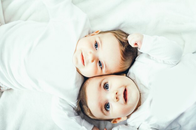 Baby twins playing on the bed 