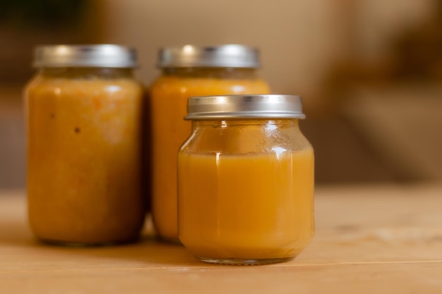 Baby vegetable and fruit puree in jars in the kitchen mockup Baby food space for text Jars of baby food on a wooden table