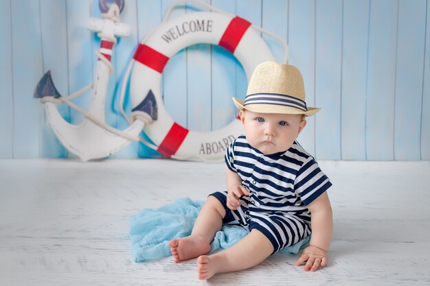 A baby in a vest next to an anchor and a lifebuoy