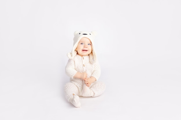 Baby in a warm suit and a bear hat on a white isolated background, space for text