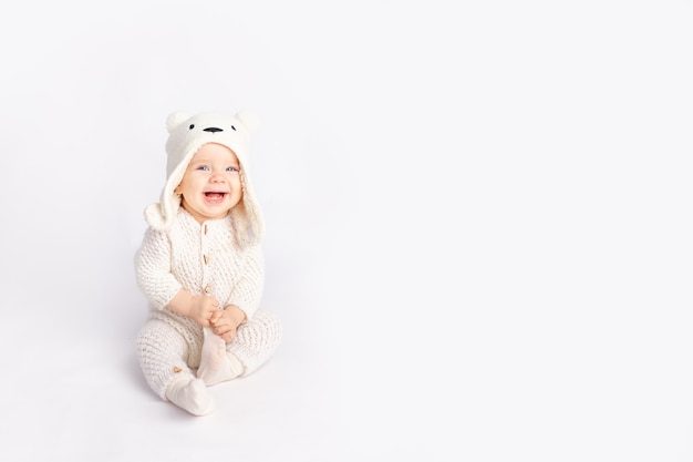 Baby in a warm suit and a bear hat on a white isolated background, space for text