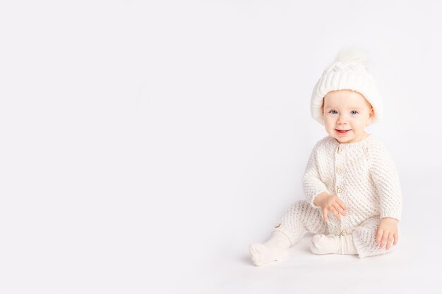 Baby in a warm suit and hat on a white isolated background, space for text