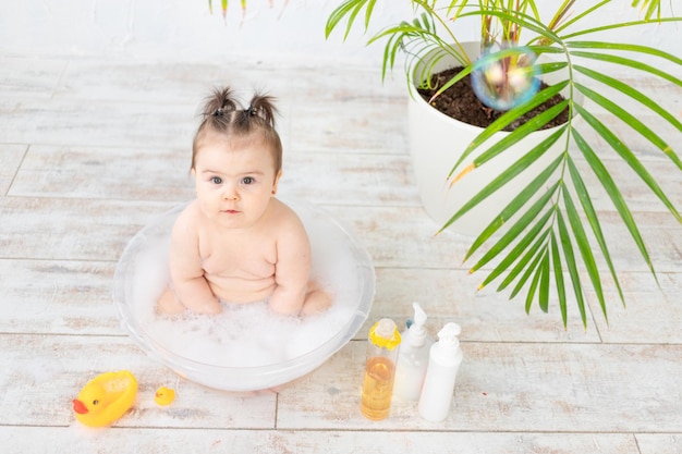 Baby washes in a bowl with foam space for text on bottles baby hygiene