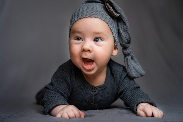 A baby wearing a gray sweater and a gray hat