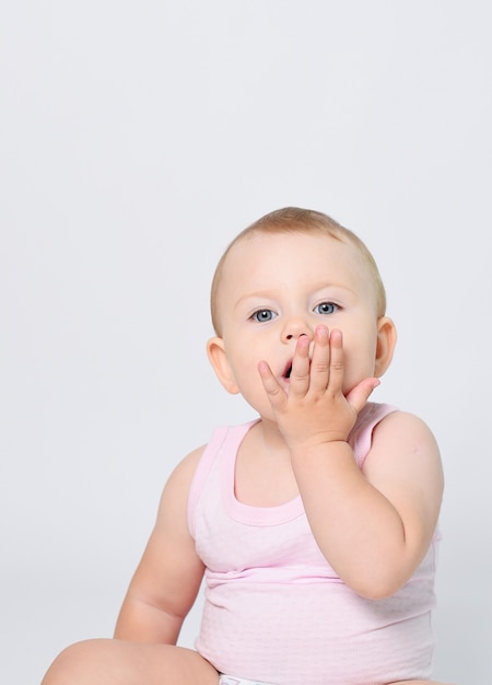 A baby on a white background in panties and a tshirt is happy and smiling