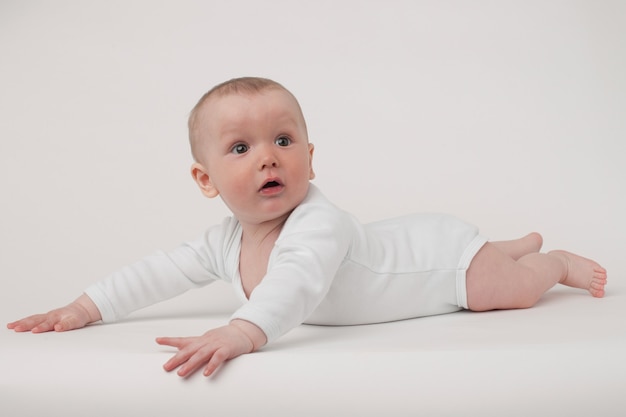 Bambino su uno sfondo bianco in un pigiama bianco