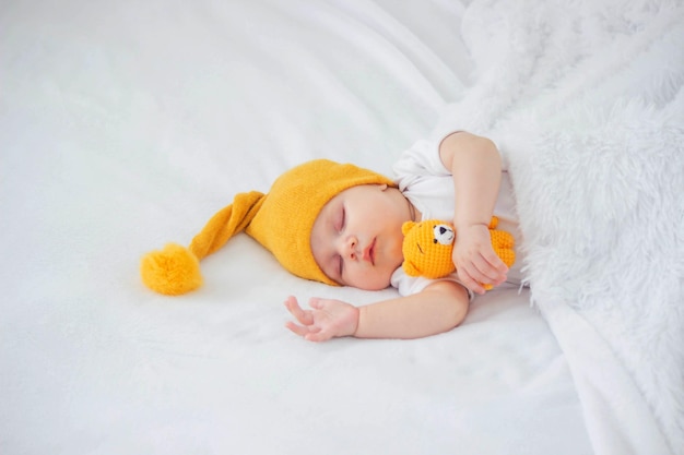 a baby in a white bodysuit is sleeping on a white background hugging a bear child