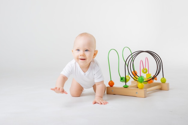 A baby in a white bodysuit plays with a multicolored educational game on a white background