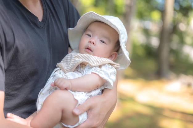 A baby in a white hat holds a baby.