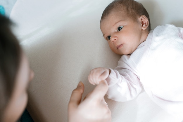 baby in white sunny bedroom resting in bed Family morning at home