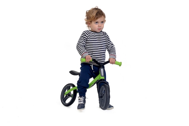 Baby who rides a bike standing on white background