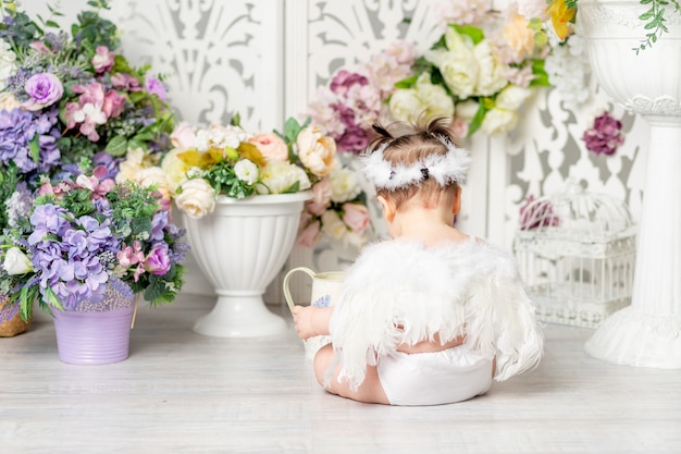 Baby with angel wings among flowers, valentine's day concept, rear view