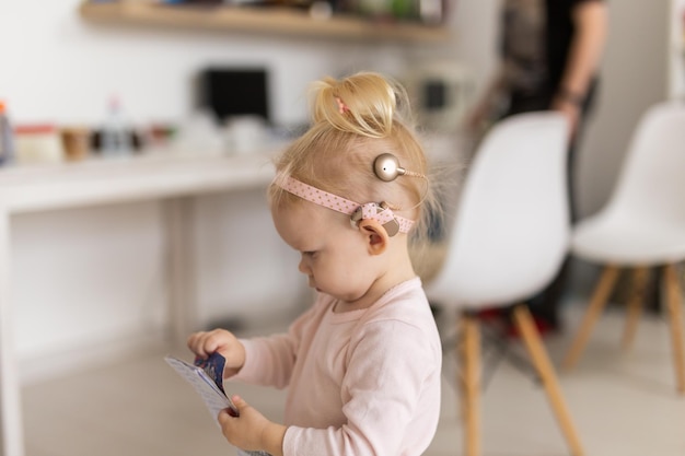 Baby with cochlear implants at home Deafness and medical technology concept