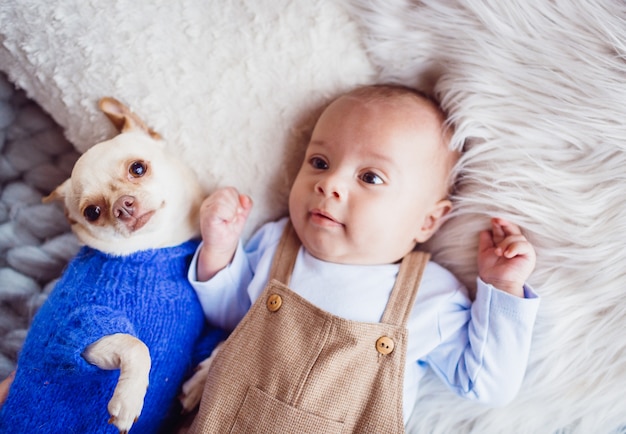 The baby with dog lie on the carpet