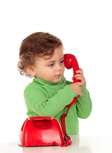 1歳の赤ちゃんが赤い電話で遊んでいる