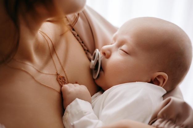 baby with pacifier in his mouth to his mother in his arms