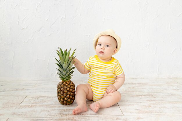 Bambino con ananas su sfondo bianco viaggi e vacanze estive concetto copia spazio