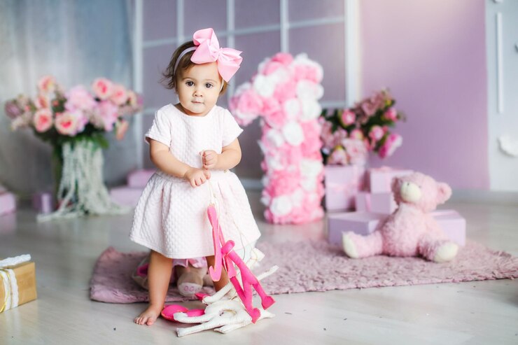 Photo baby with a pink dress on a background of pink adornment with a pink bow on her head