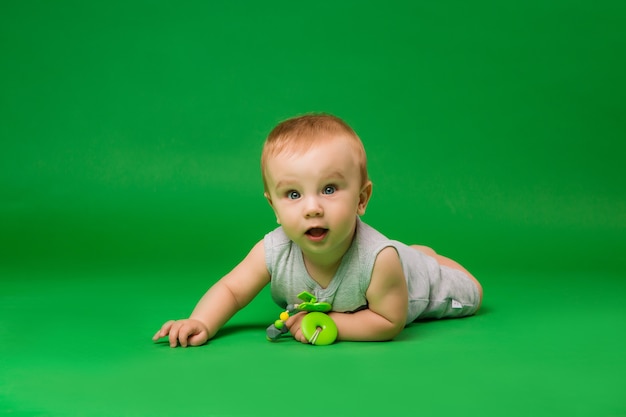 Baby with a toy on a green wall