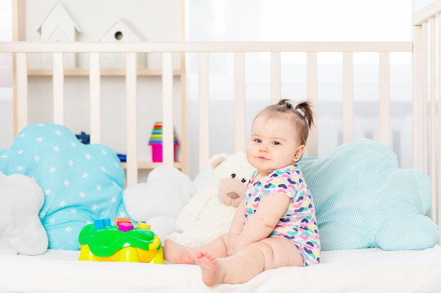 Ребенок с игрушками в кроватке дома