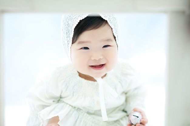 A baby with a white background and a white hat is playing a game.