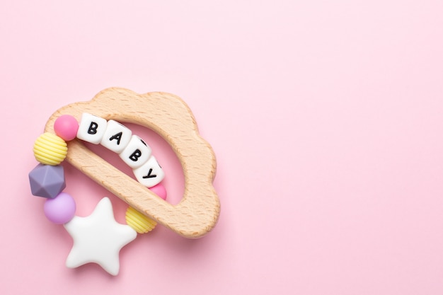 Baby wooden toy and teethers pastel colors on pink