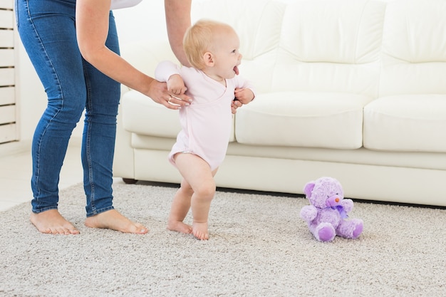 Baby zet eerste stapjes met hulp van moeder thuis