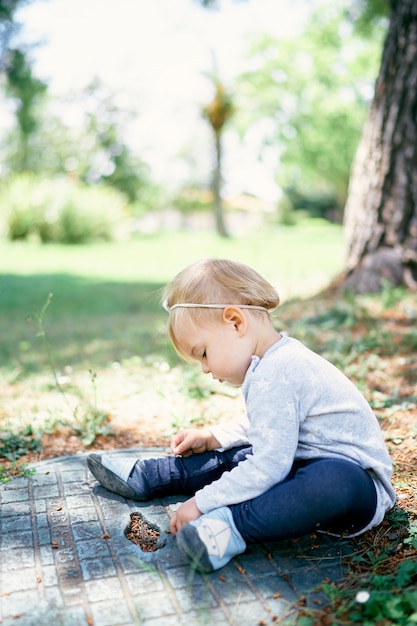 Baby zit op een mangat in het zijaanzicht van een groen park