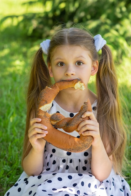 Baby zit op het gras en eet gretig een bagel met maanzaad in de frisse lucht.