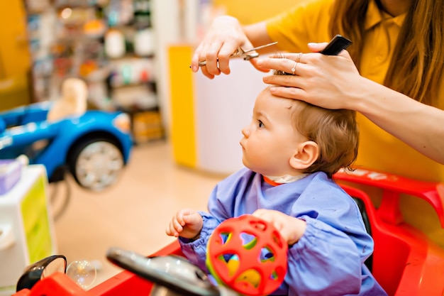 Il primo taglio di capelli di baby39 ragazzino carino dal parrucchiere professionista per bambini