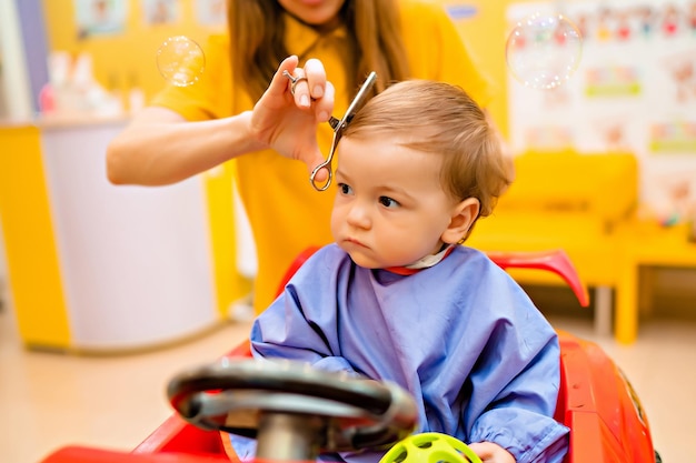 Il primo taglio di capelli di baby39 ragazzino carino dal parrucchiere professionista per bambini