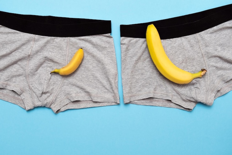 Foto babybanaan vergelijk grootte met grote banaan op mannelijk slipje op blauwe achtergrond