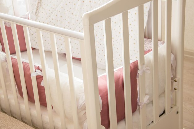 Foto babybedje met witte en bourgogne kleur kussens met veters