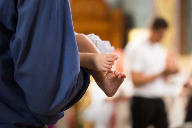 Babybenen op de handen van peetouders in de kathedraal