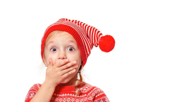 Foto la bambina con il cappello di babbo natale chiuse la bocca con la mano sorpresa