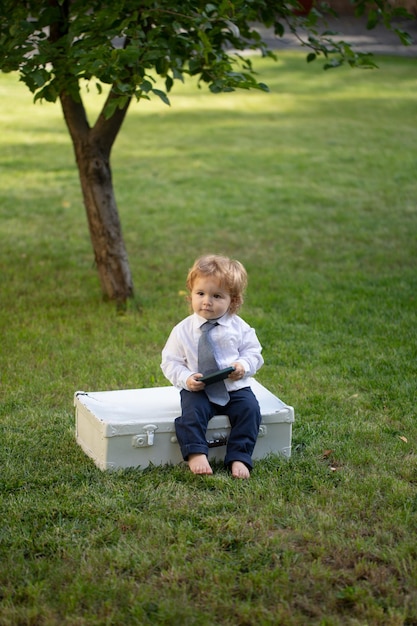 Babyin suit and necktie tie in green grass child having fun on family picnic in summer garden cute b