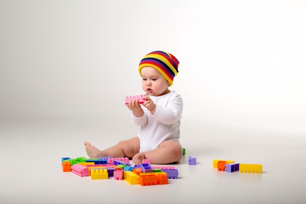 babyjongen 9 maanden oud spelen met een veelkleurige aannemer op een witte muur